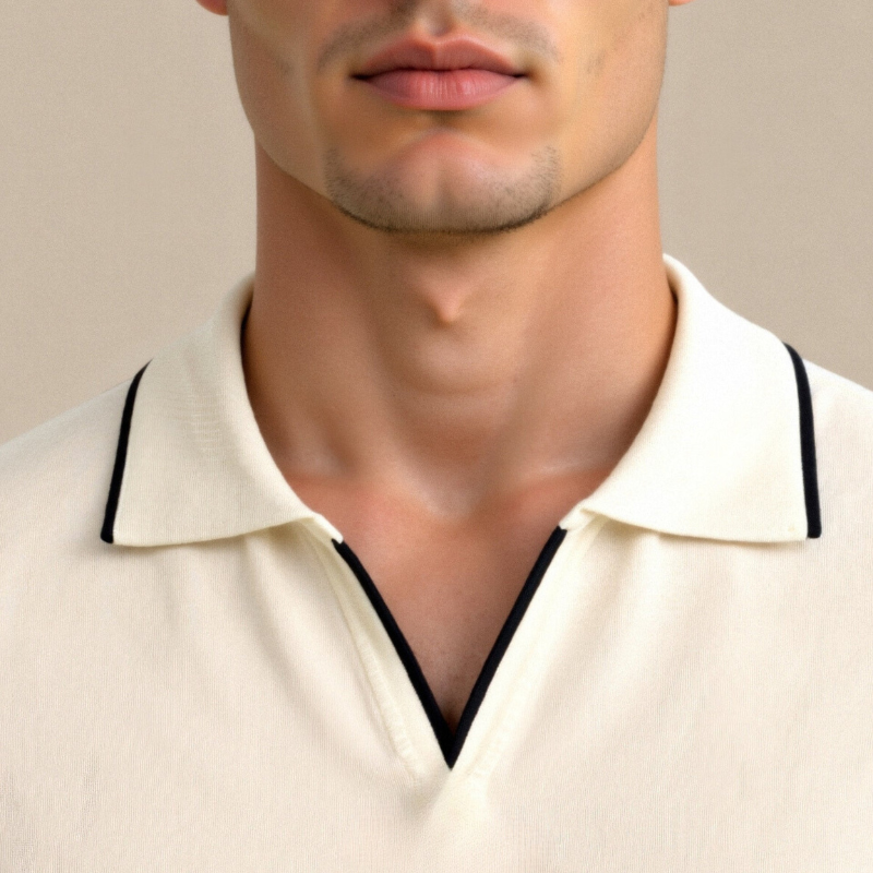 Zbliżenie na kołnierzyk kremowej koszulki polo z czarnymi lamówkami.