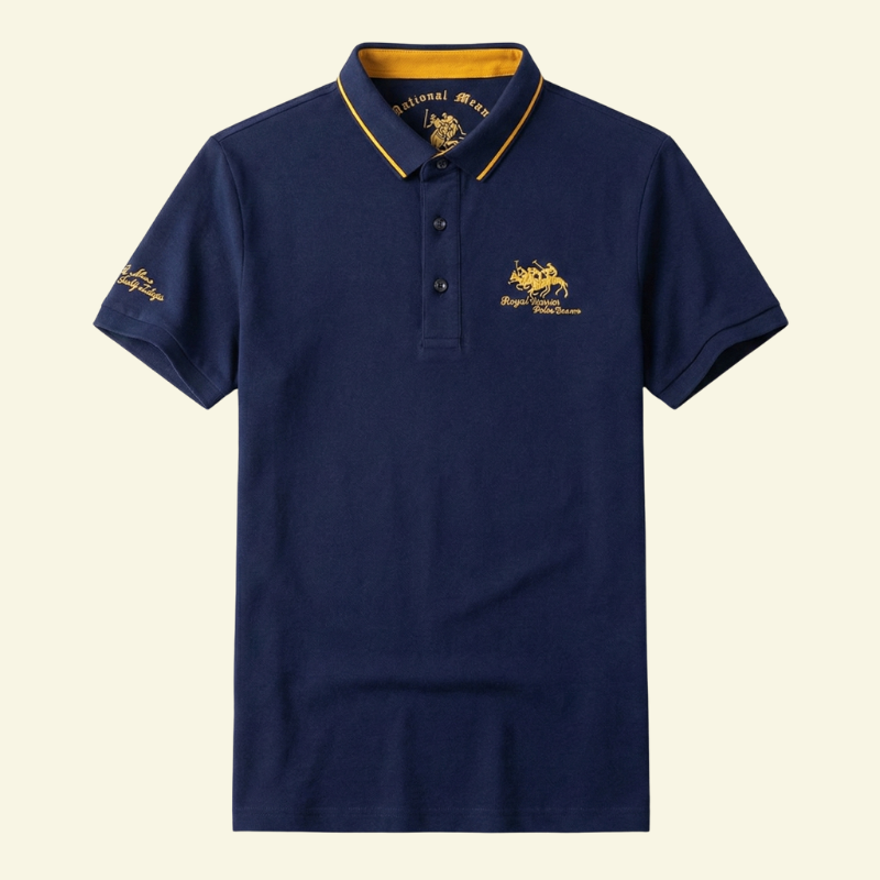 Granatowa koszulka polo z haftem na piersi i kontrastowym kołnierzykiem, ułożona na płasko na jasnym tle.