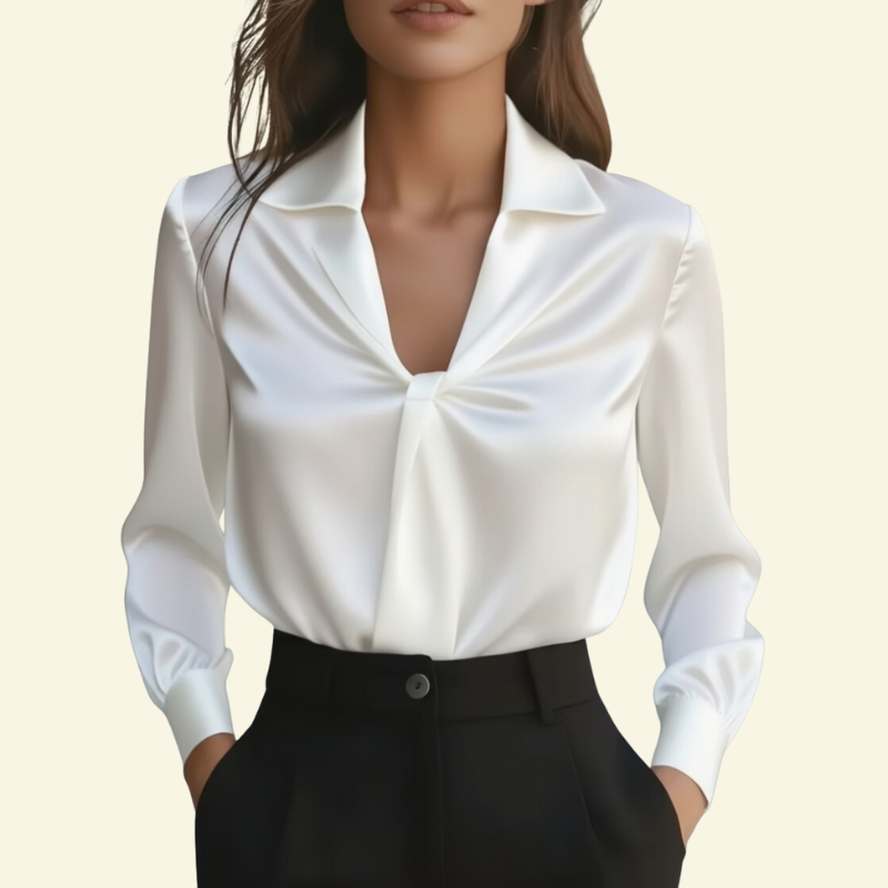 Modelka w białej bluzce z frontowym skręceniem i dekoltem V, stojąca w minimalistycznym studio; bluzka zestawiona z czarnymi spodniami.