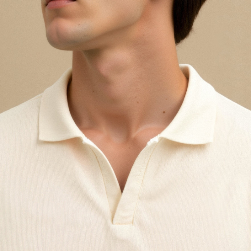 Zbliżenie na kołnierzyk kremowej koszulki polo z widoczną fakturą dzianiny.