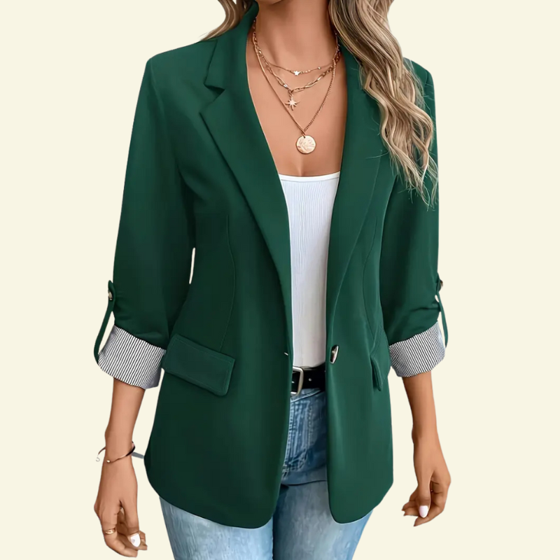 Modelka w zielonej marynarce, ujęcie od przodu w lekkiej pozie, ręka przy torbie.