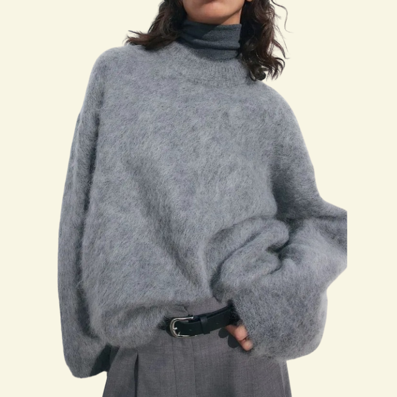 Modelka w srebrzystoszarym, oversize’owym swetrze o mohairowej fakturze — miękki, luźny krój i puszysta powierzchnia podkreślająca wygodę.