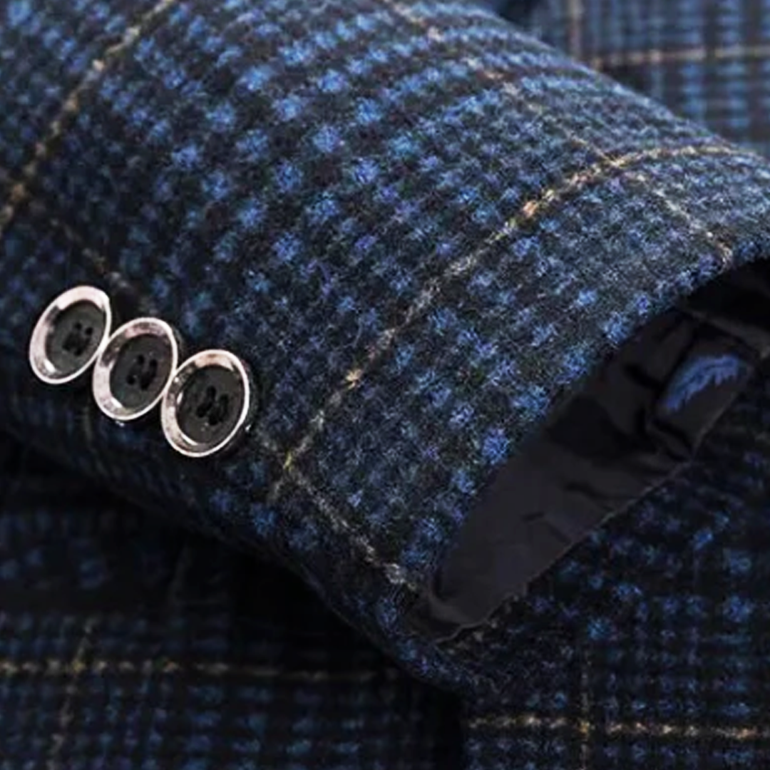 Zbliżenie na rękaw marynarki w granatową kratę z potrójnym rzędem metalowych guzików.