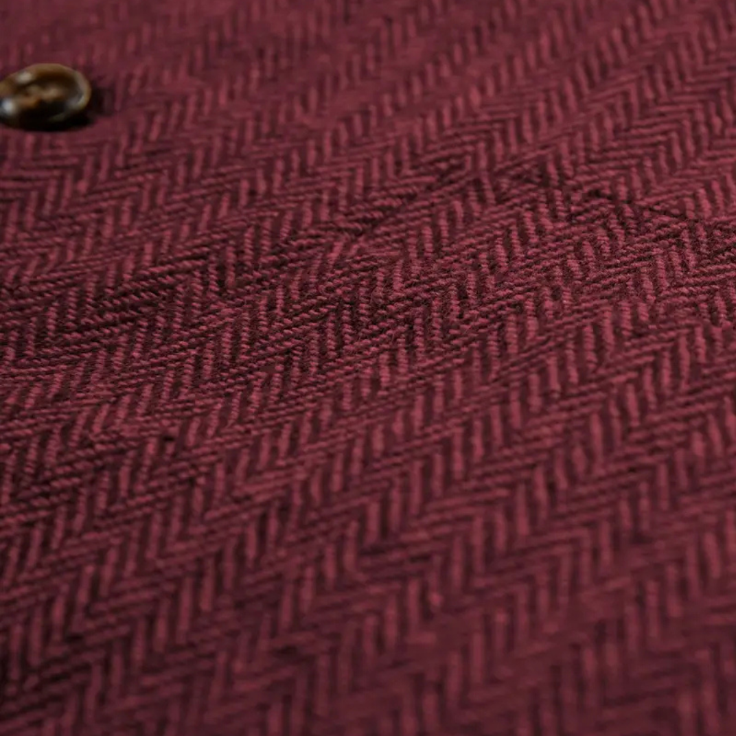 Zbliżenie na fakturę bordowej tweedowej tkaniny z widocznym splotem.