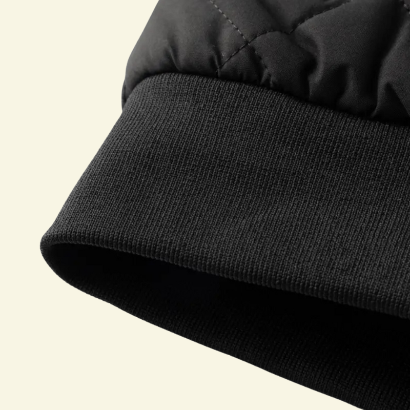 Zbliżenie na dół kurtki wykończony elastycznym, czarnym ściągaczem zapewniającym dopasowanie.