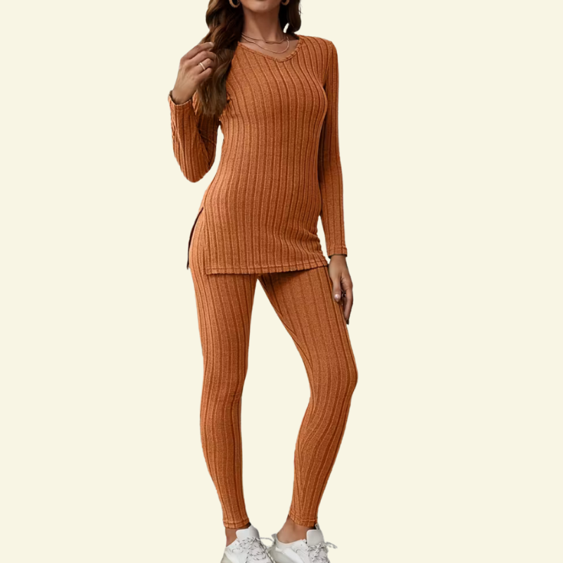 Modelka w ceglastopomarańczowym prążkowanym komplecie, tunika z długim rękawem i dopasowane legginsy w pełnym ujęciu.