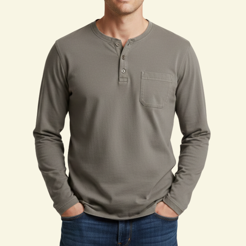 Model w beżowo-szarej koszulce Henley, ujęcie od przodu z rękami w kieszeniach.