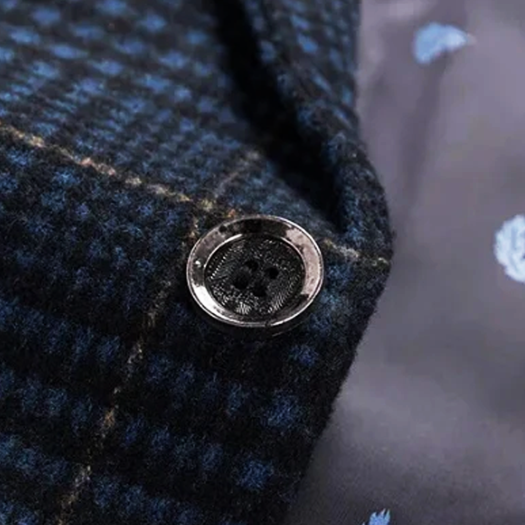 Detal przedniego guzika marynarki w granatową kratę, z widoczną strukturą tkaniny.